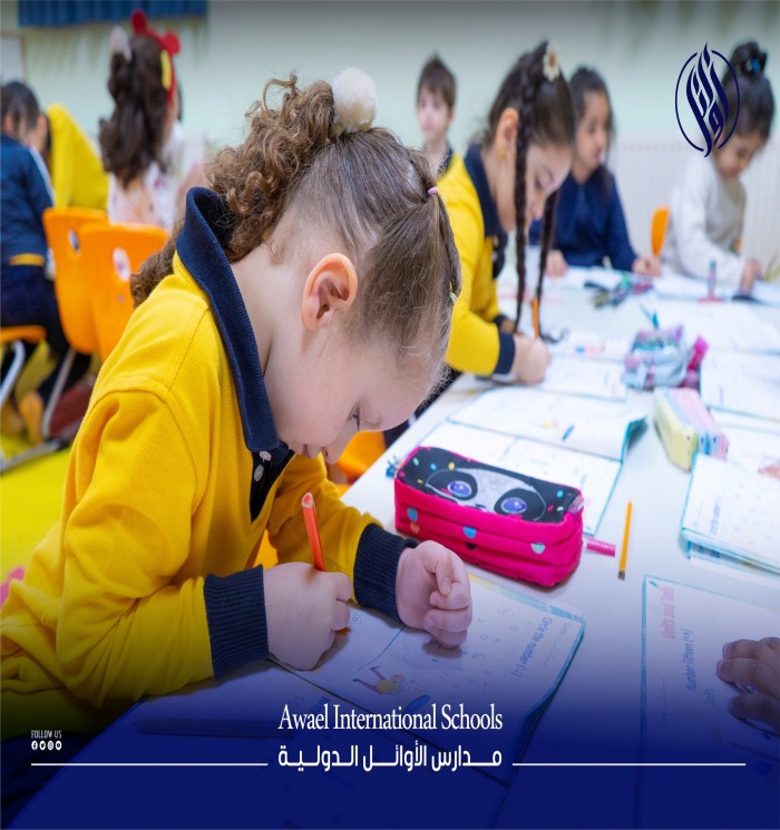In the Awael nursery, a group of young children sit on their chairs inside the classroom